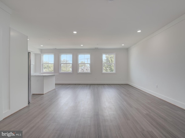 unfurnished living room with ornamental molding, light hardwood / wood-style flooring, and a wealth of natural light