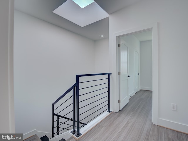 hallway with a skylight and light hardwood / wood-style flooring