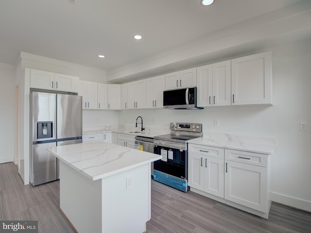 kitchen featuring a kitchen island, stainless steel appliances, sink, light wood-type flooring, and white cabinets