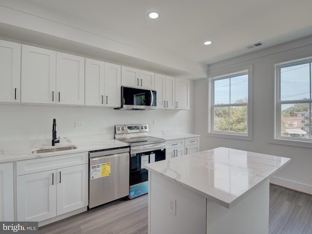 kitchen with light wood-type flooring, white cabinets, stainless steel appliances, and sink