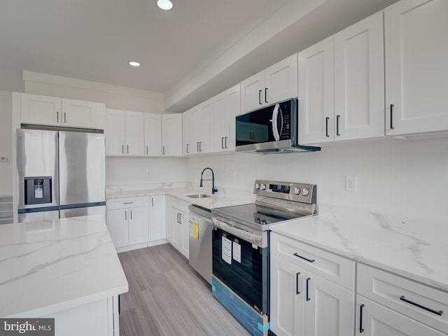 kitchen with light wood-type flooring, white cabinets, and stainless steel appliances