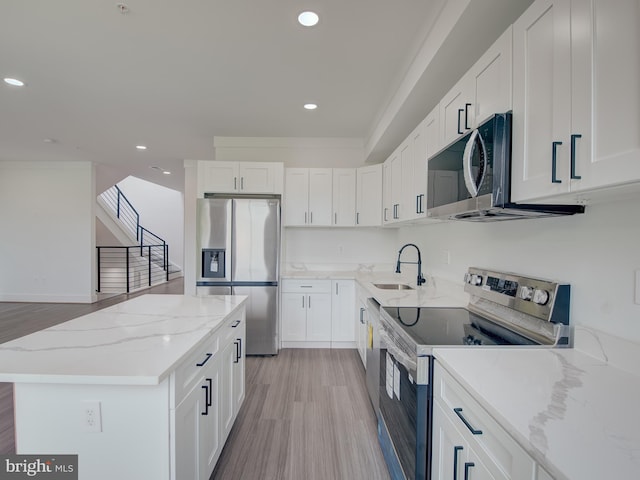 kitchen featuring light hardwood / wood-style flooring, stainless steel appliances, light stone countertops, and white cabinets