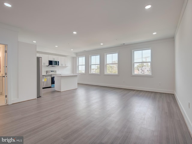 unfurnished living room featuring crown molding and light hardwood / wood-style flooring