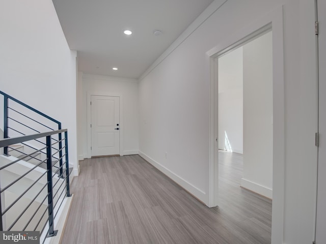 hallway with light wood-type flooring and crown molding