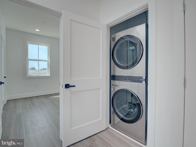 laundry area featuring stacked washer / dryer and light wood-type flooring