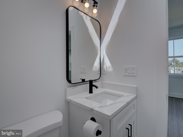 bathroom with toilet, hardwood / wood-style flooring, and vanity