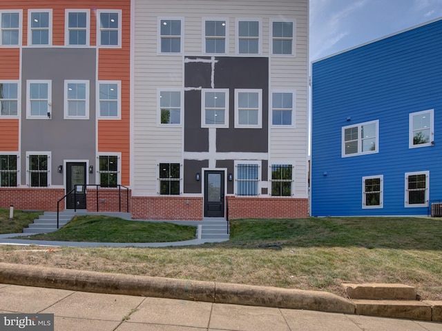 view of front of home with central AC and a front yard