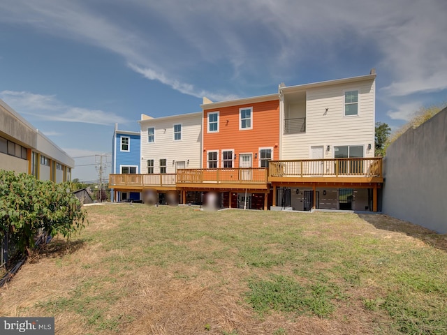 rear view of property featuring a lawn and a deck