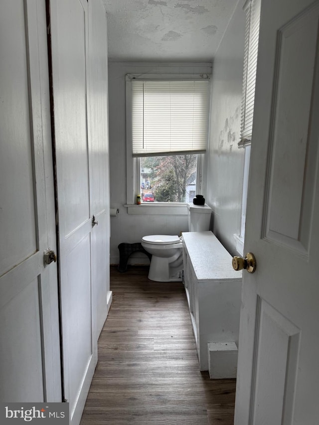 bathroom with toilet, a textured ceiling, and wood finished floors