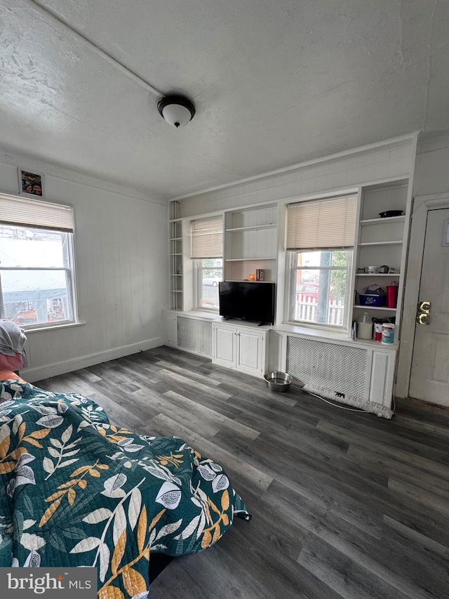 unfurnished bedroom featuring radiator, a textured ceiling, baseboards, and dark wood-type flooring