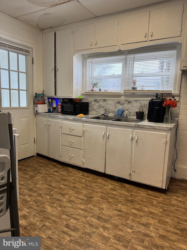 kitchen featuring light countertops, dark wood-type flooring, white cabinets, a sink, and black microwave