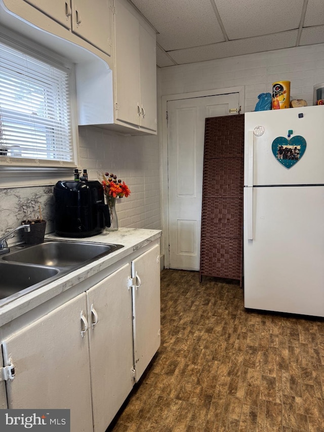 kitchen with a paneled ceiling, a sink, white cabinetry, light countertops, and freestanding refrigerator