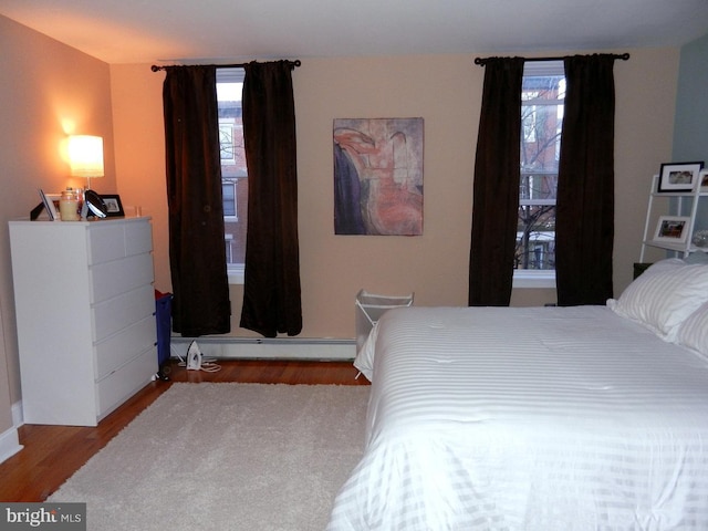 bedroom with light hardwood / wood-style floors and a baseboard radiator