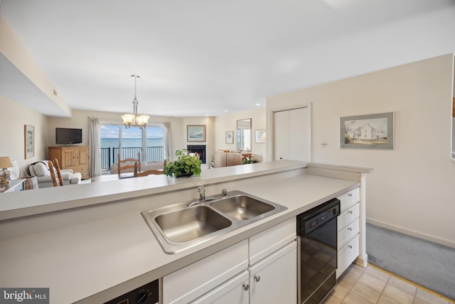 kitchen featuring black dishwasher, sink, a notable chandelier, pendant lighting, and white cabinets