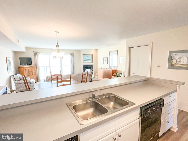 kitchen featuring open floor plan, dishwasher, light countertops, white cabinets, and a sink