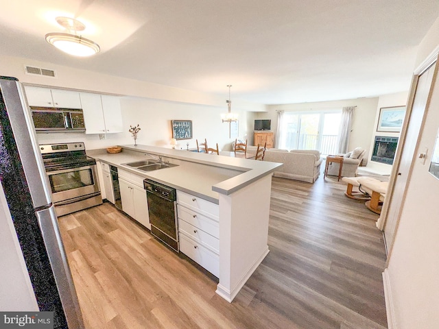 kitchen featuring visible vents, a sink, stainless steel electric range, a peninsula, and dishwasher