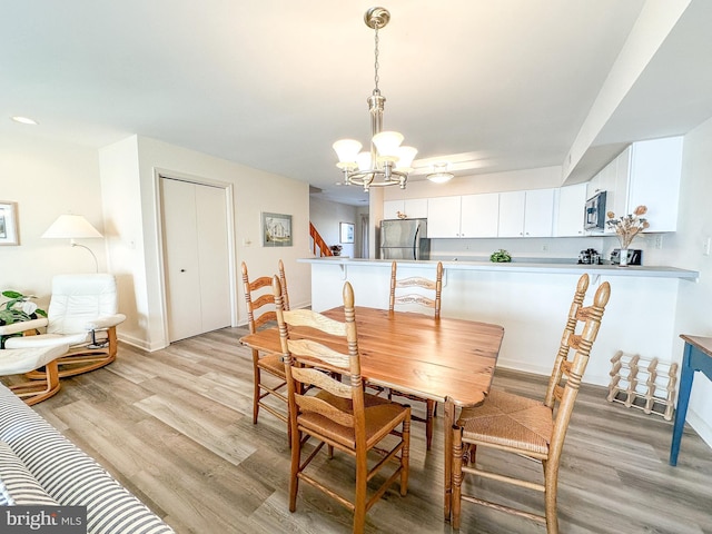 dining room featuring an inviting chandelier, light wood-style flooring, and baseboards