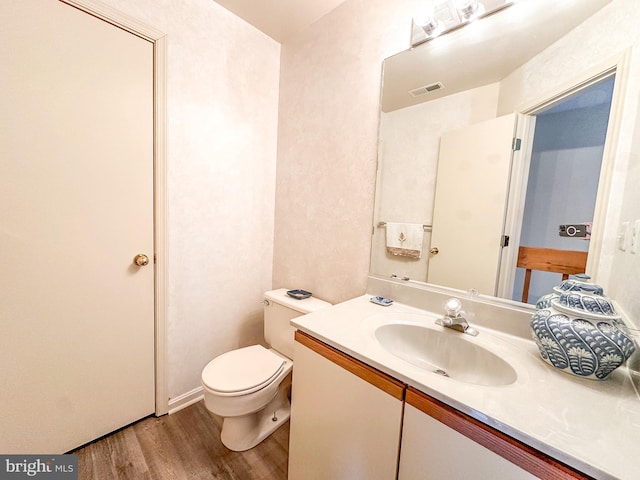 bathroom featuring visible vents, toilet, wood finished floors, and vanity