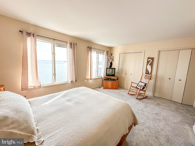 bedroom featuring multiple closets and light carpet