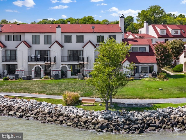 back of property with central air condition unit, a yard, a water view, and a balcony