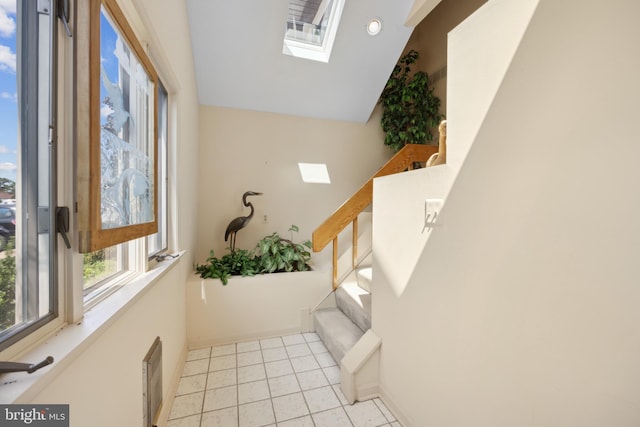 stairway featuring a skylight and tile patterned flooring