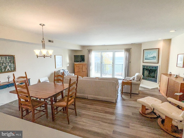 dining space with a chandelier, visible vents, a fireplace, and wood finished floors