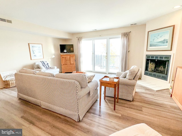 living area with visible vents, a fireplace, and wood finished floors