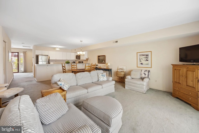 carpeted living room with an inviting chandelier