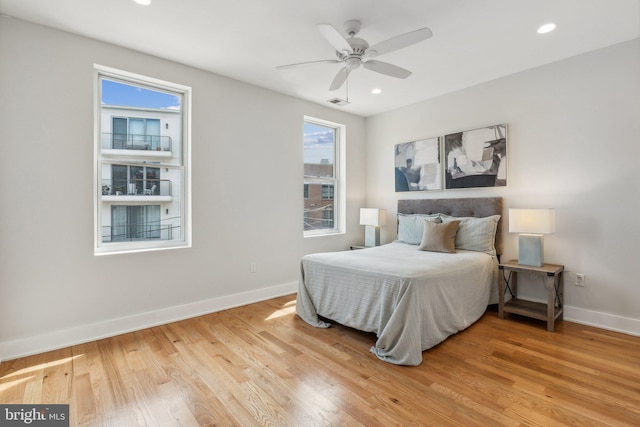 bedroom featuring light wood-type flooring, multiple windows, and ceiling fan