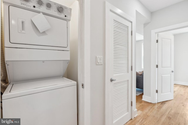 washroom with stacked washer / dryer and light hardwood / wood-style flooring