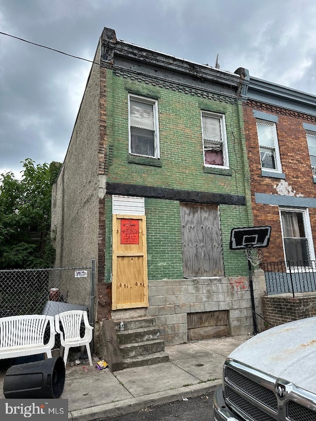 townhome / multi-family property featuring entry steps, brick siding, and fence