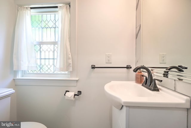 bathroom featuring vanity, toilet, and a healthy amount of sunlight