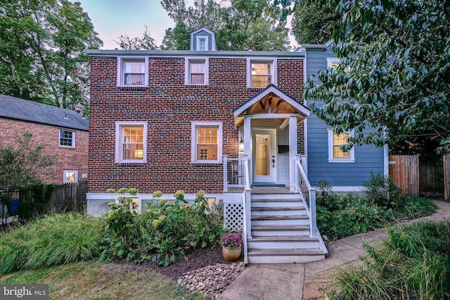 view of front of home featuring brick siding and fence