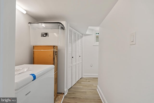 clothes washing area with washer / dryer and light hardwood / wood-style flooring