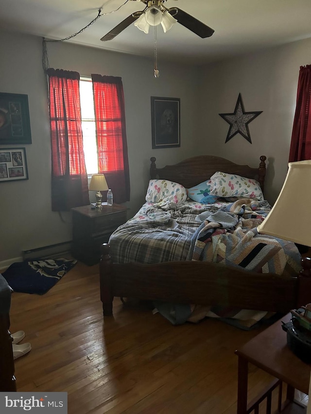 bedroom with ceiling fan, baseboard heating, and wood finished floors