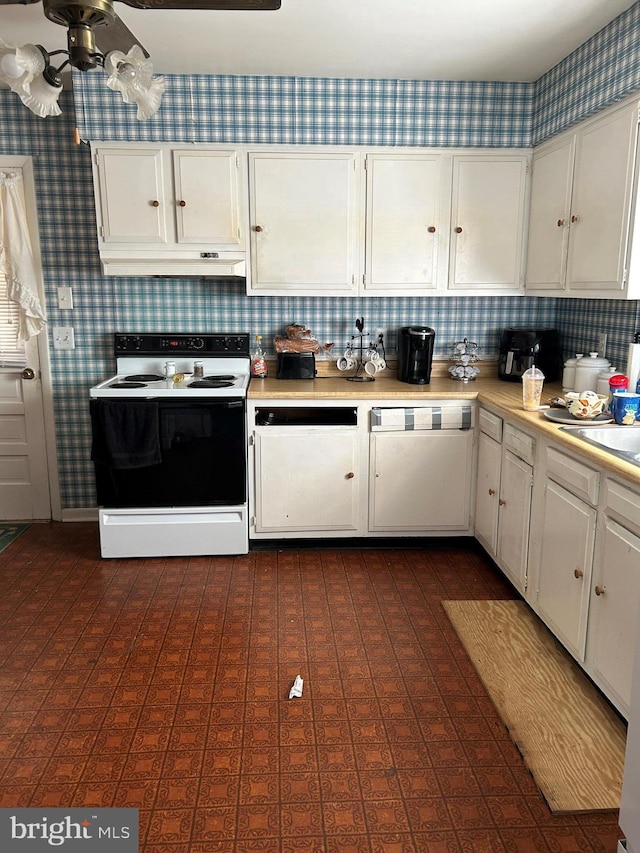 kitchen featuring light countertops, range with electric cooktop, white cabinets, and wallpapered walls