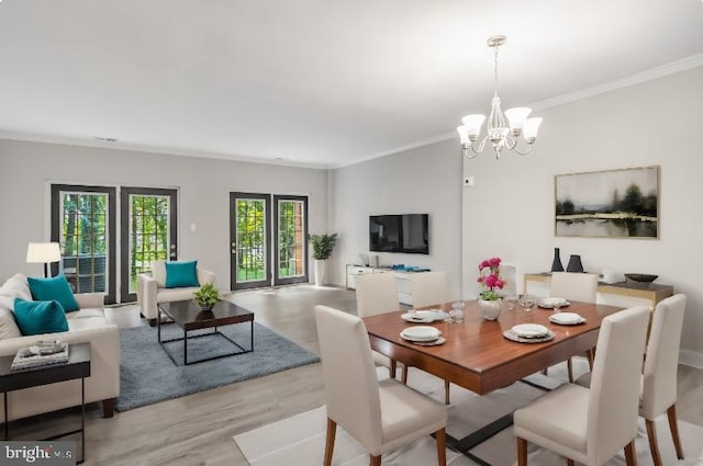 dining room featuring crown molding, an inviting chandelier, and light wood-style floors