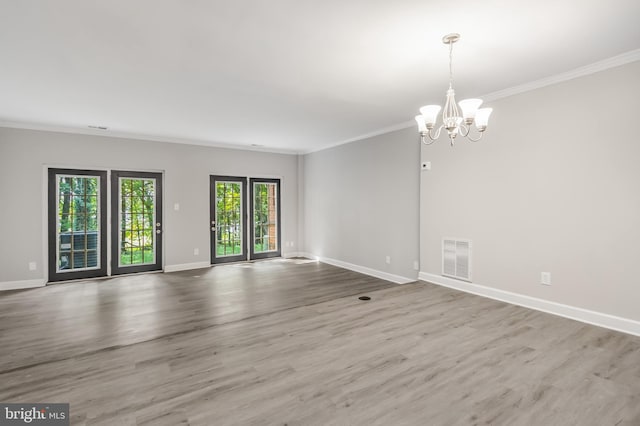 spare room with hardwood / wood-style flooring, a chandelier, and ornamental molding