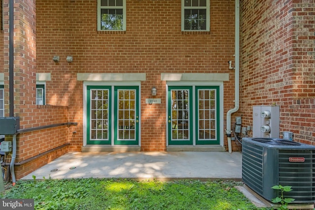 entrance to property with french doors, a patio, and central AC unit