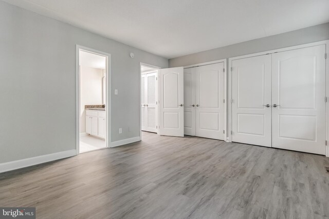 unfurnished bedroom with light hardwood / wood-style flooring and connected bathroom