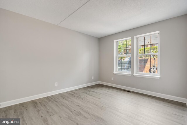 unfurnished room with a textured ceiling and light hardwood / wood-style floors