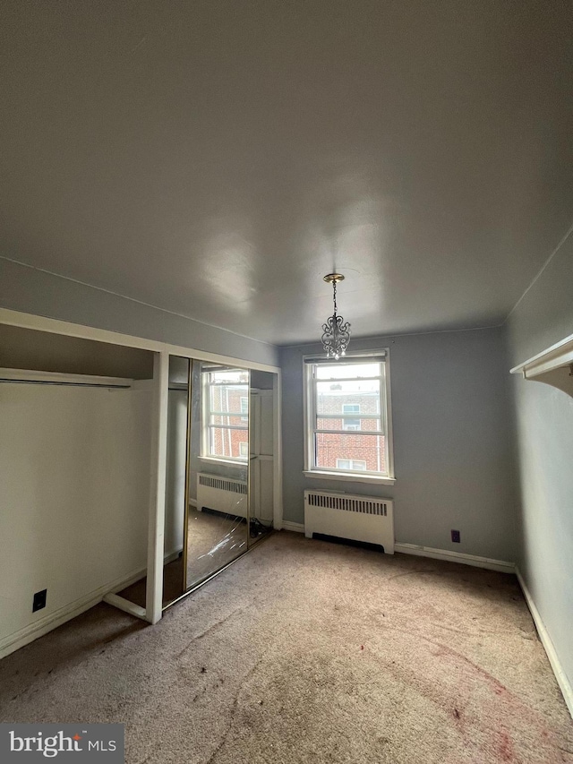 unfurnished bedroom with a notable chandelier, carpet, and radiator heating unit