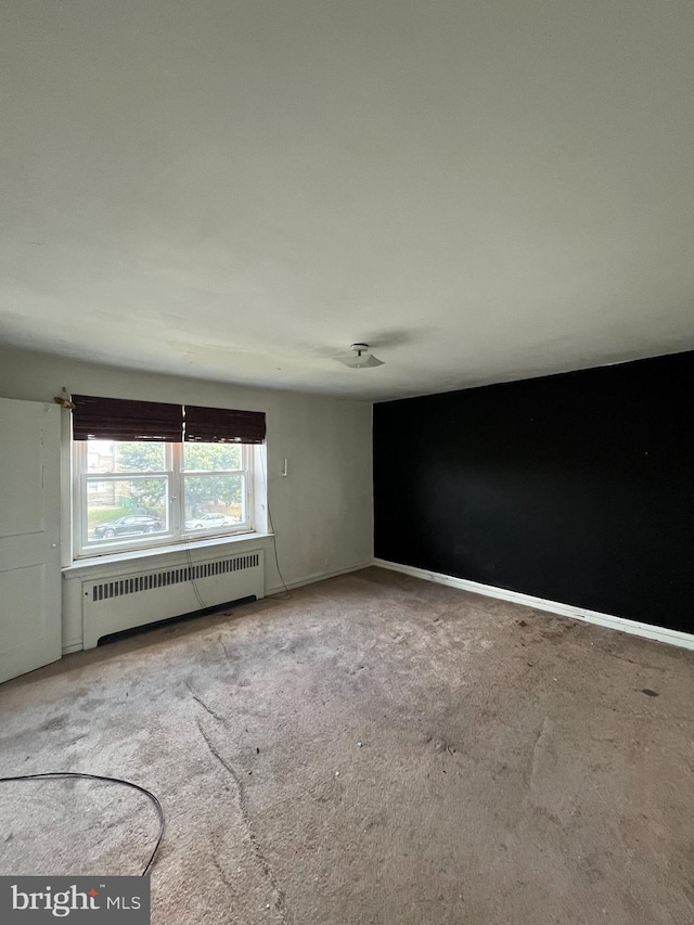 unfurnished room featuring carpet flooring and radiator heating unit