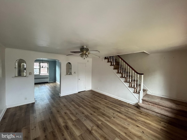 unfurnished living room with ceiling fan, dark wood-type flooring, and radiator heating unit