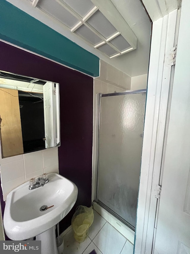 bathroom featuring walk in shower, decorative backsplash, sink, and tile patterned floors