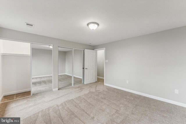 unfurnished bedroom with light colored carpet and multiple closets