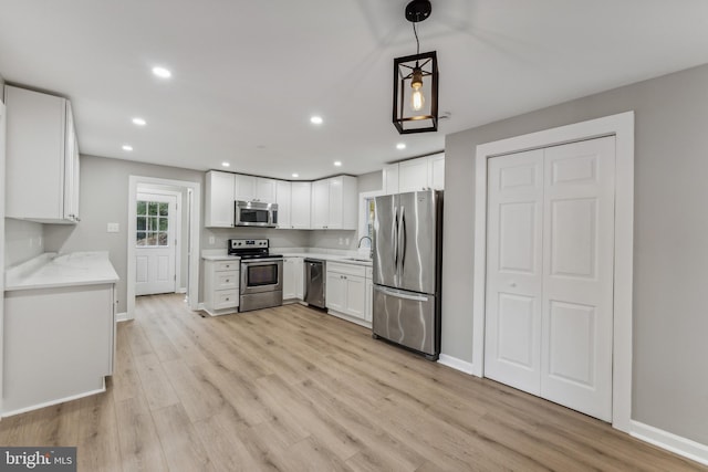 kitchen with appliances with stainless steel finishes, light hardwood / wood-style floors, and white cabinetry