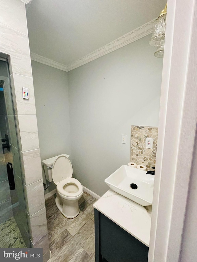 bathroom with hardwood / wood-style floors, an enclosed shower, toilet, vanity, and crown molding