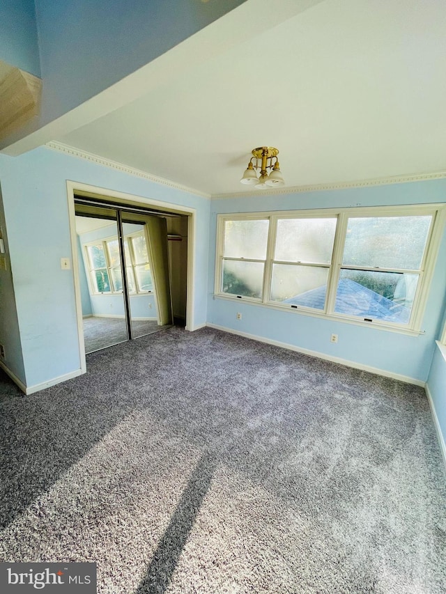 unfurnished bedroom featuring a closet, crown molding, carpet, and multiple windows