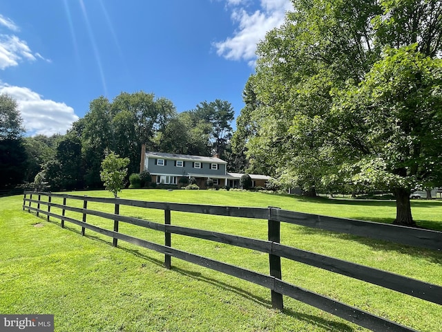 view of gate with a lawn and a rural view